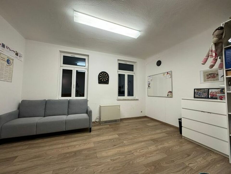 zu sehen ist eine Innenaufnahme des Gruppenraums mit Sofa, Whiteboard und Stauraumregal